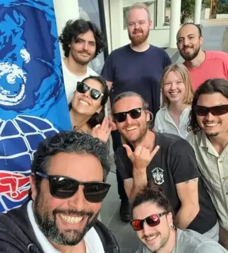 Groupe de personnes souriantes posant devant un drapeau bleu et blanc