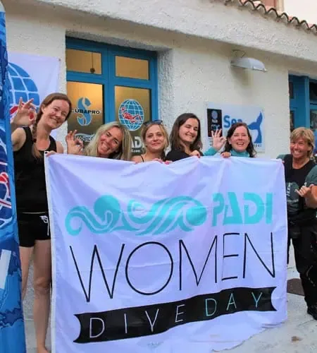 Groupe de femmes souriantes tenant une bannière PADI Women Dive Day