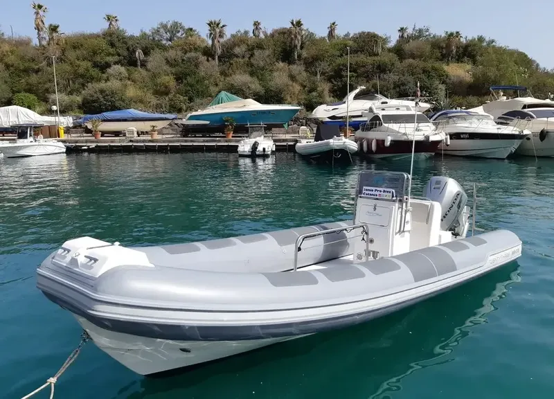 Bateau semi-rigide gris amarré dans un port ensoleillé avec d'autres bateaux