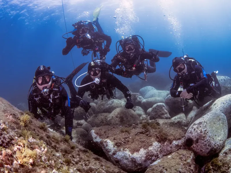 Groupe de plongeurs explorant un fond marin rocheux ensoleillé