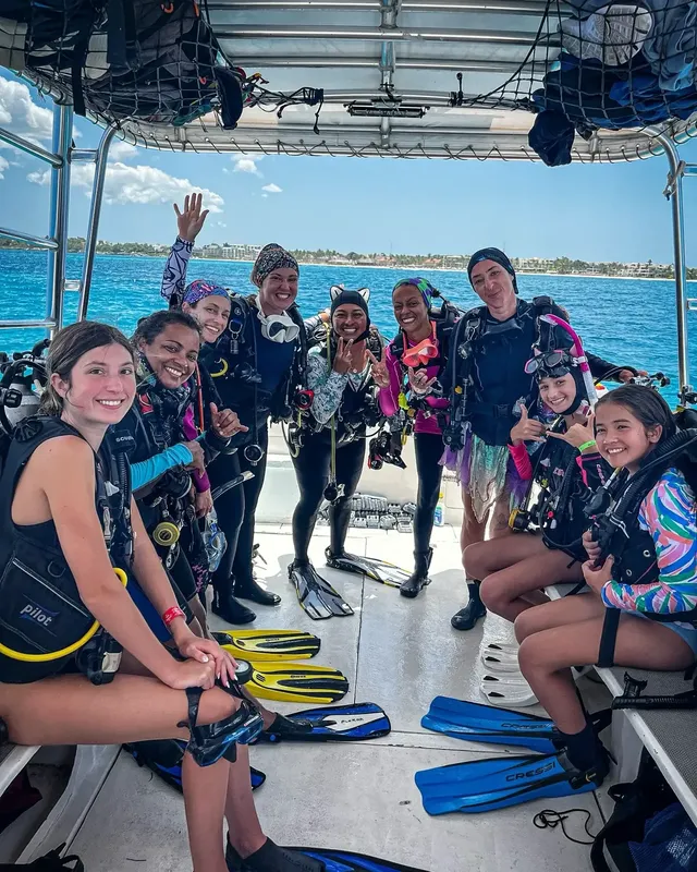 Groupe de plongeurs souriants sur un bateau en mer, équipement visible