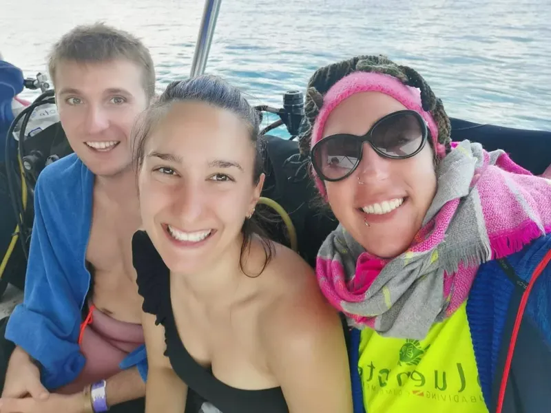 Trois plongeurs souriants à bord d'un bateau en mer