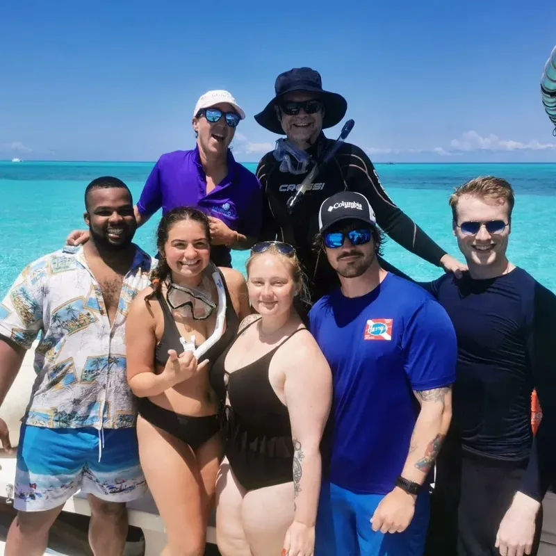 Groupe de personnes souriantes sur un bateau en mer turquoise