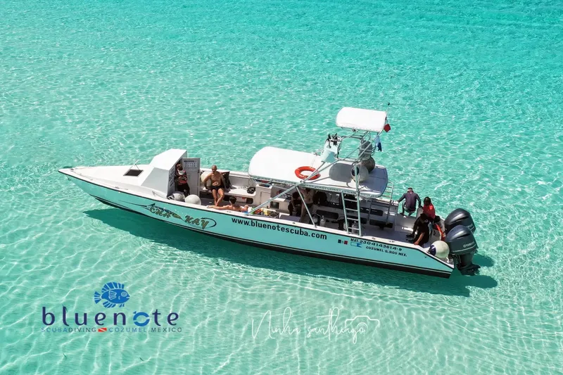 Bateau de plongée orange avec des passagers en mer turquoise claire