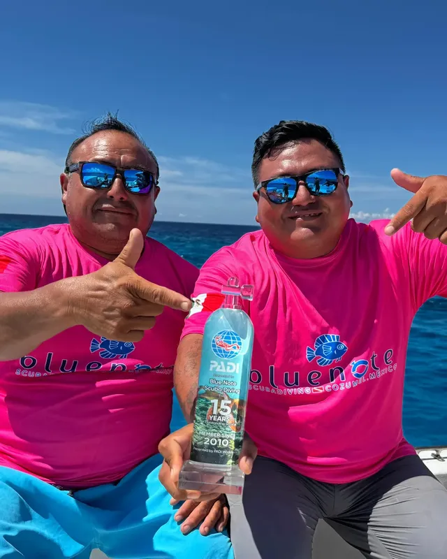 Deux hommes souriants avec un trophée PADI sur un bateau