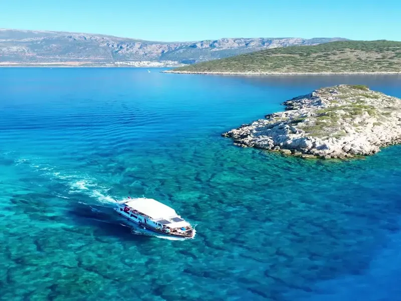 Bateau de plongée navigue dans une eau turquoise près d'îlots rocheux