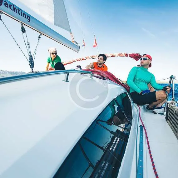 Trois personnes sur un voilier en mer, ciel bleu et soleil