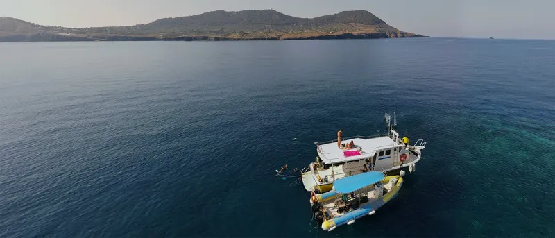 Bateau de plongée en mer avec des plongeurs et une côte rocheuse