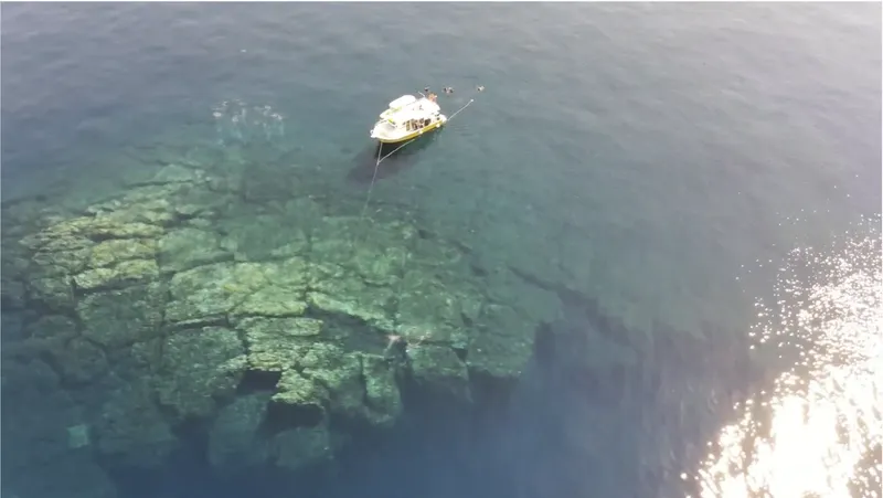 Vue aérienne d'un bateau de plongée au-dessus d'un fond rocheux clair