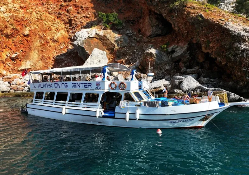 Bateau de plongée blanc et bleu amarré près de falaises rocheuses