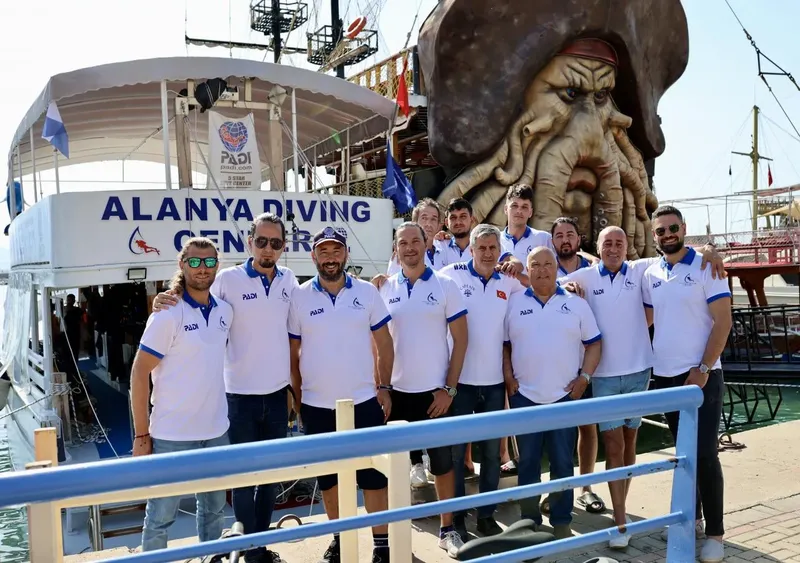 Groupe de personnes souriantes posant devant un bateau de plongée