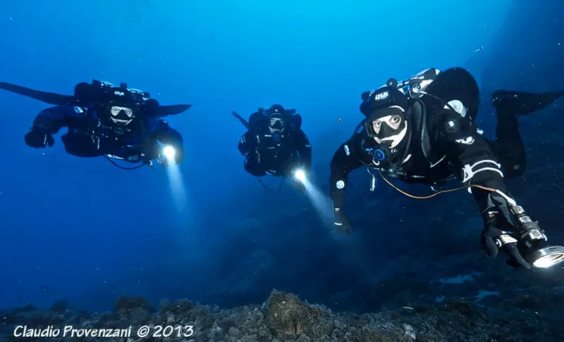 Trois plongeurs explorent les profondeurs marines avec leurs lampes torches