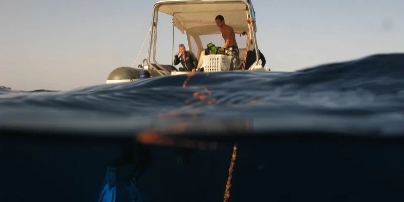 Deux plongeurs sur un bateau, vue mi-immergée, préparation plongée