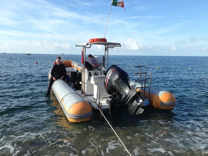 Plongeur s'apprête à monter à bord d'un bateau pneumatique jaune et blanc