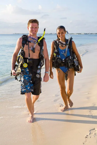 Deux plongeurs marchant sur une plage avec leur équipement complet