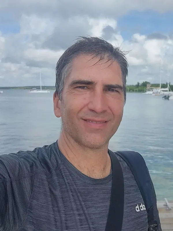 Portrait d'un homme souriant devant des bateaux amarrés au port