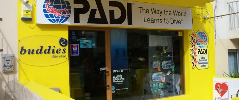 Façade jaune d'un centre de plongée avec logos PADI et matériel visible