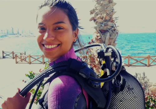 Jeune femme souriante avec équipement de plongée sur fond marin
