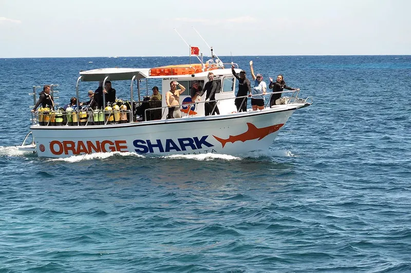 Bateau de plongée orange avec des plongeurs et du matériel à bord