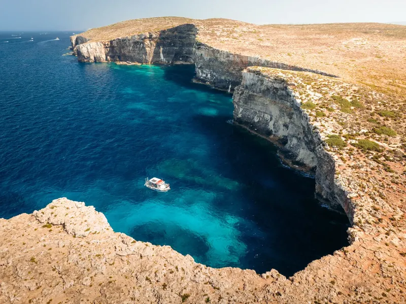 Vue aérienne d'une falaise rocheuse surplombant une eau turquoise et un bateau