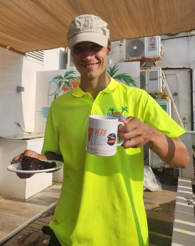 Un homme souriant tient une tasse et une part de gâteau