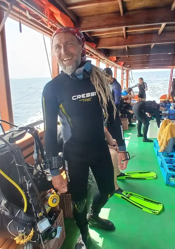 Plongeur souriant en combinaison, prêt à plonger en mer