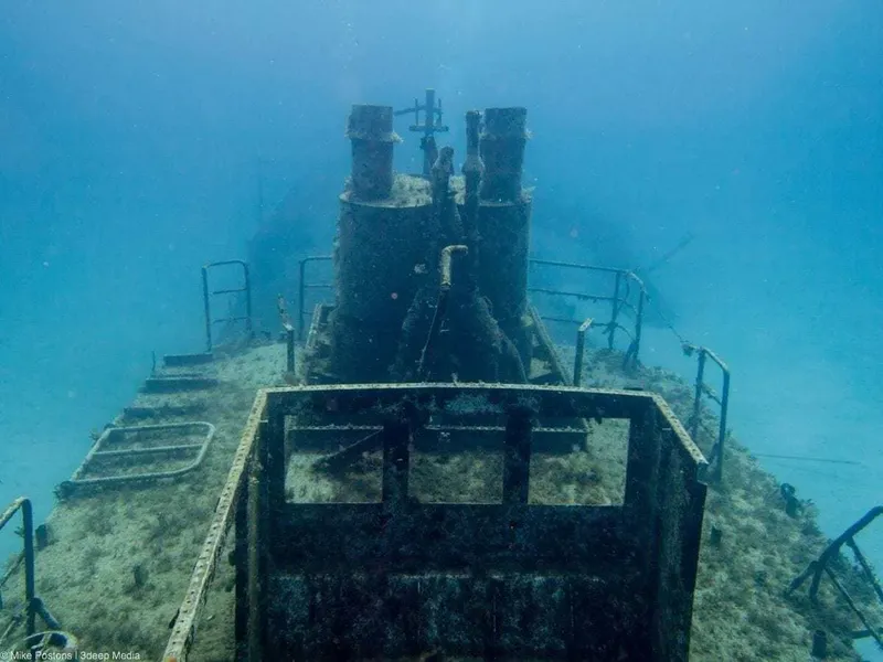 Epave de bateau rouillé reposant sur le fond marin bleu clair