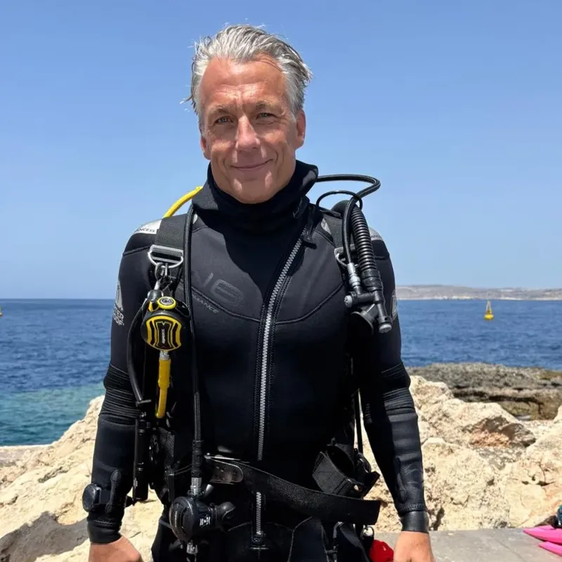 Plongeur souriant en combinaison, équipé, regardant vers l'objectif