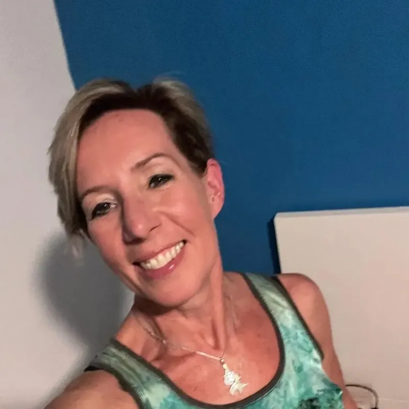 Portrait souriant d'une femme blonde devant un mur bleu clair