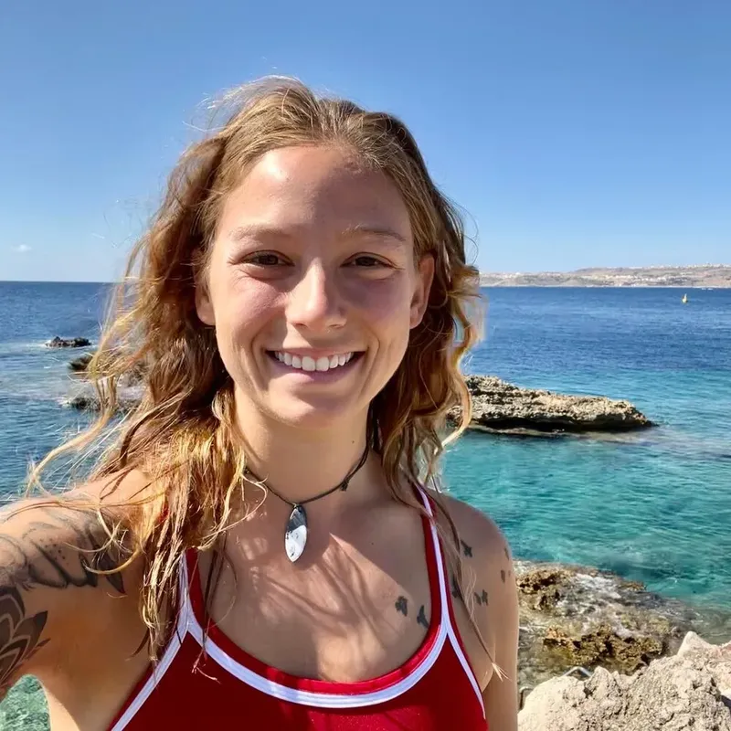 Jeune femme souriante, cheveux longs, en bord de mer ensoleillée
