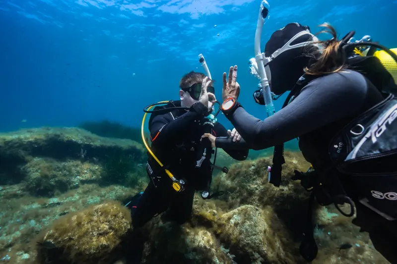 Deux plongeurs communiquent sous l'eau avec des signes de la main