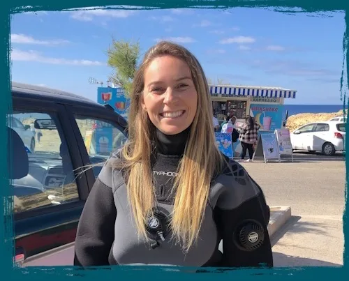 Plongeuse souriante en combinaison près d'un snack et de voitures