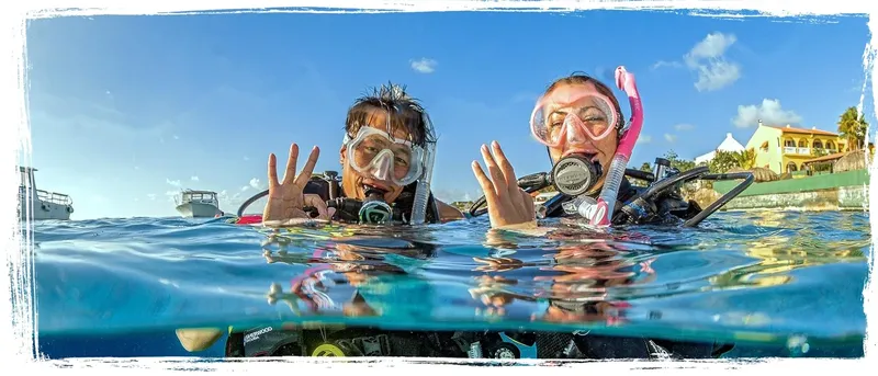 Deux plongeurs souriants font des signes sous la surface de l'eau