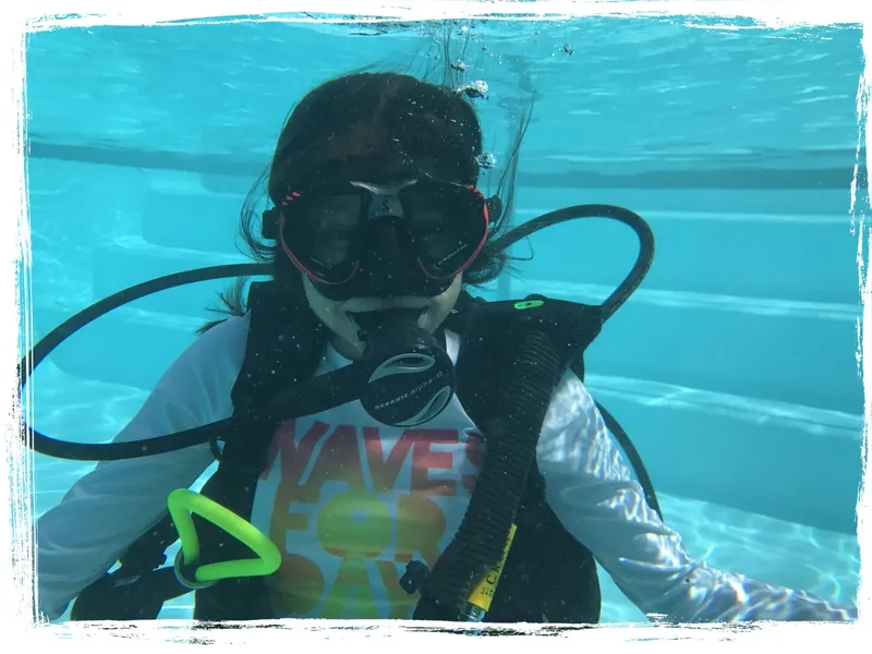 Plongeuse avec masque et détendeur, nageant sous l'eau en piscine