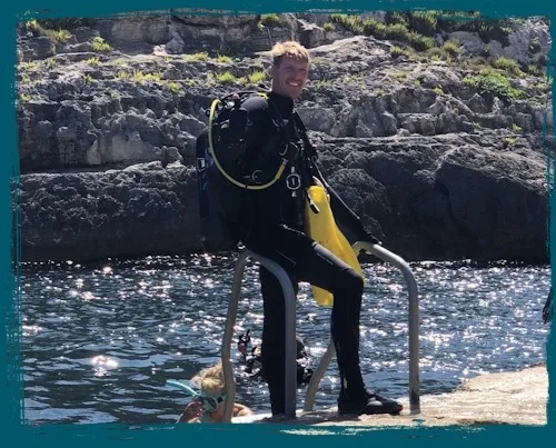 Plongeur équipé sortant de l'eau avec un sourire et une bouée jaune