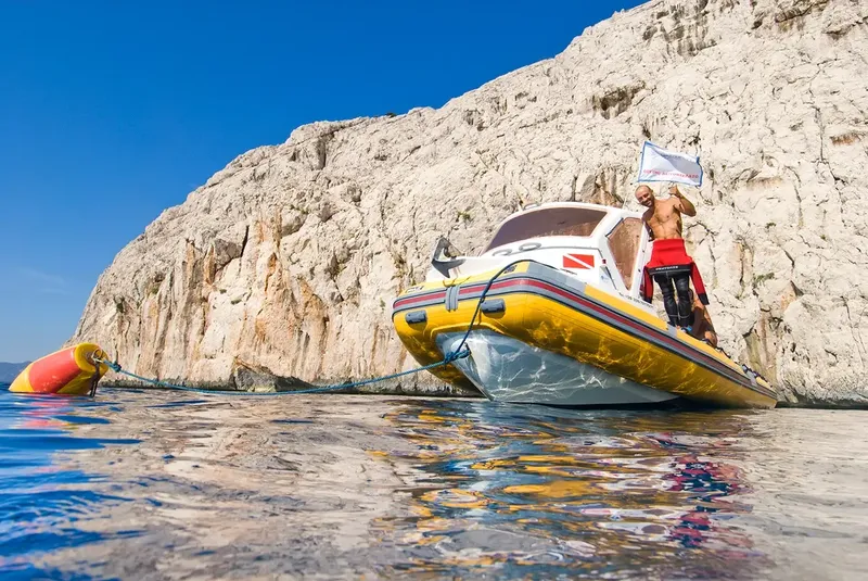 Homme sur un bateau de plongée, levant un drapeau blanc en mer
