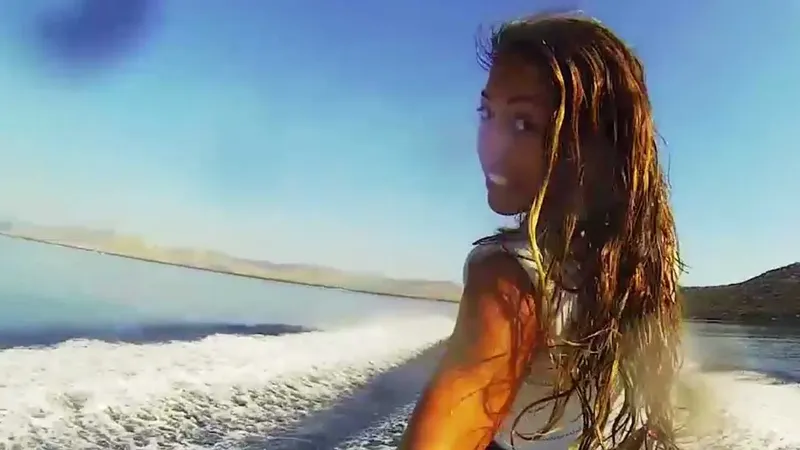 Jeune femme souriante en mer, cheveux mouillés, regard vers l'horizon