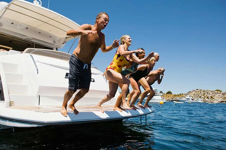 Groupe de personnes sautant d'un bateau en mer par beau temps