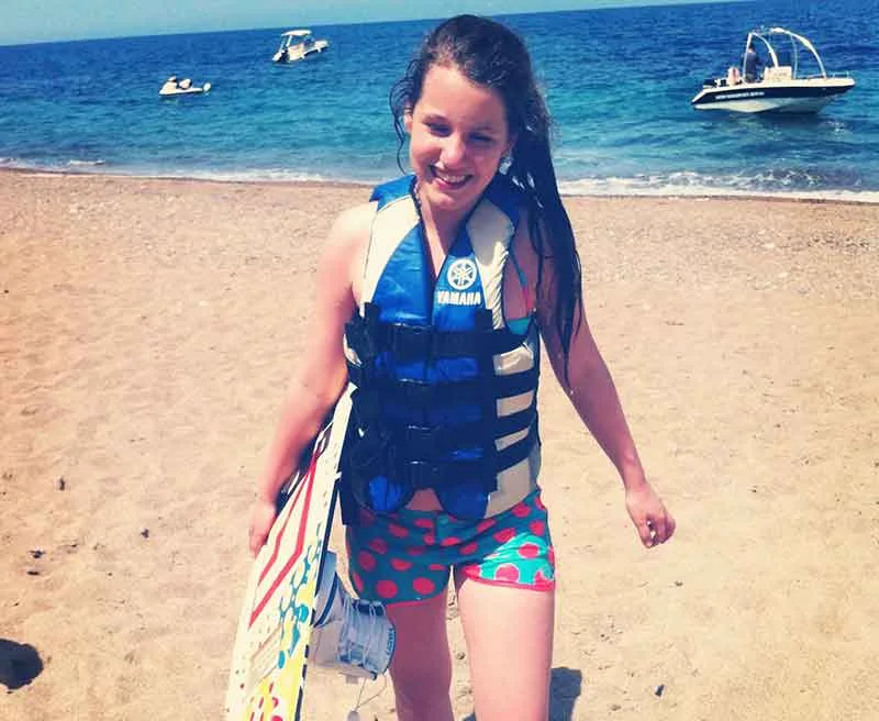 Jeune fille souriante sur une plage avec gilet de sauvetage