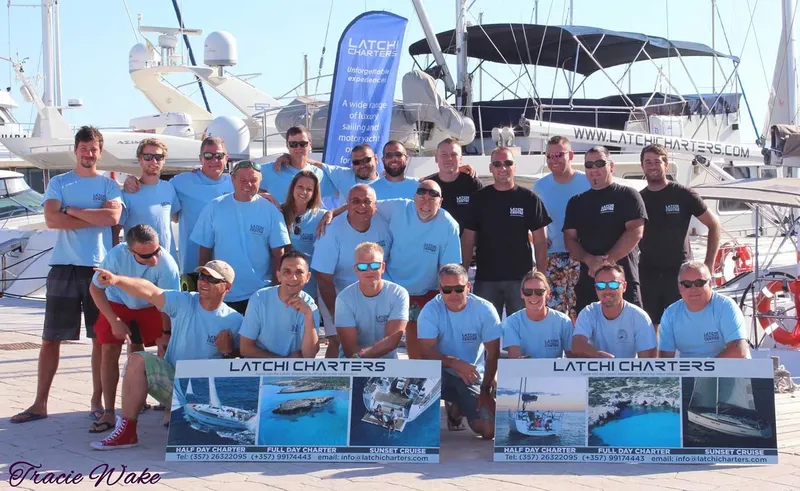 Groupe de personnes souriantes posant devant des yachts au port