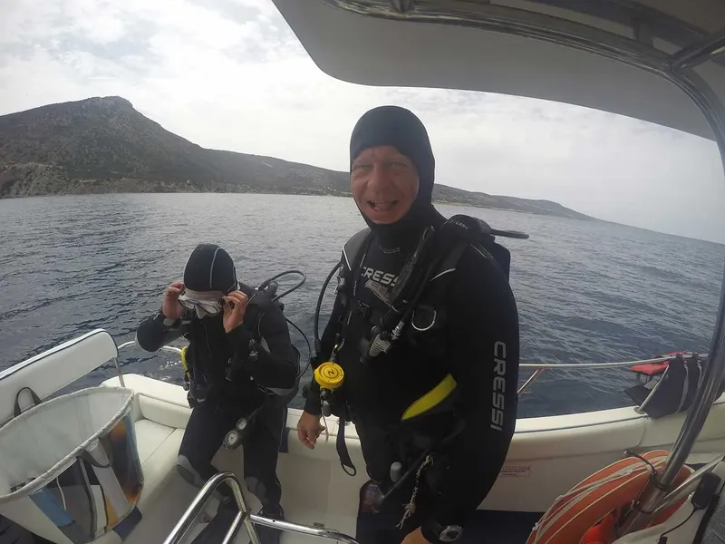 Deux plongeurs en combinaison se préparent à bord d'un bateau