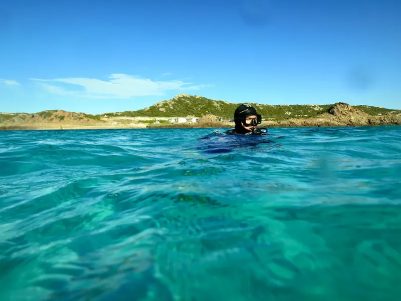 Plongeur en surface, visage visible, eau turquoise, ciel bleu clair