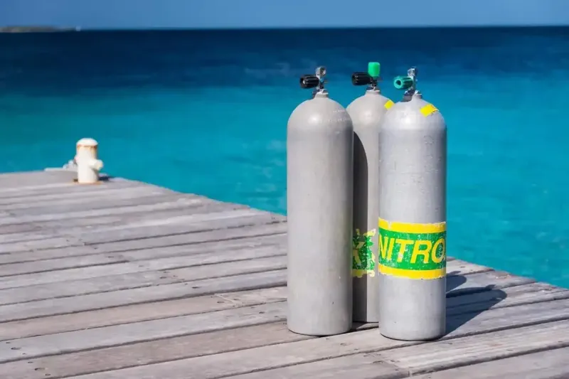 Bouteilles de plongée sur un ponton en bois face à la mer
