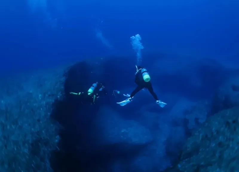 Deux plongeurs explorent un récif rocheux en profondeur sous l'eau