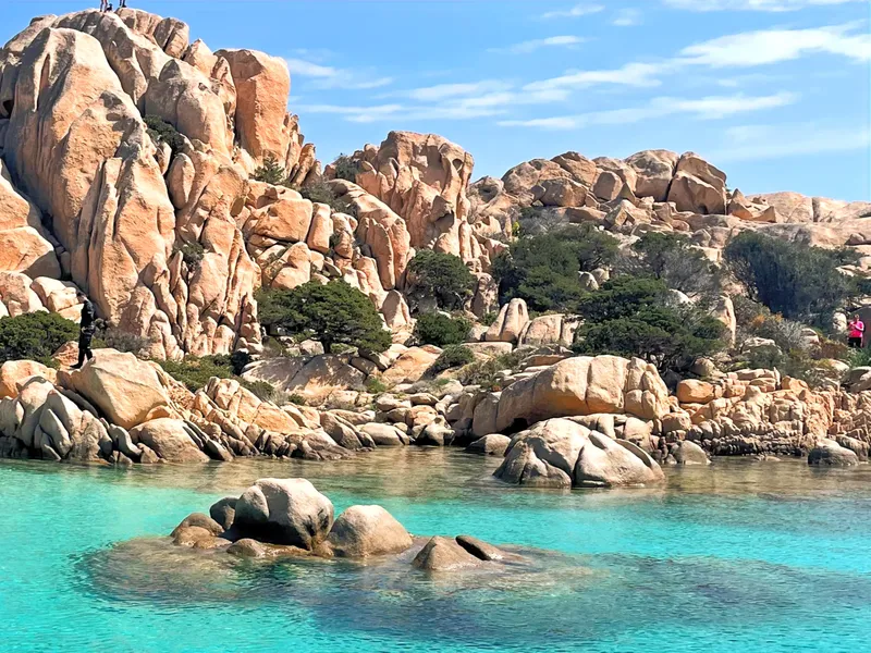 Côte rocheuse avec eau turquoise et quelques personnes en randonnée
