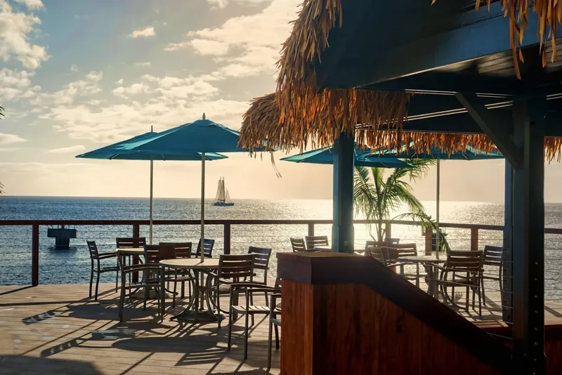 Terrasse ombragée avec vue sur la mer et un voilier au loin