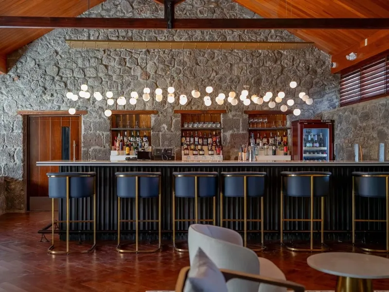 Bar spacieux avec comptoir noir, tabourets bleus et éclairage chaleureux