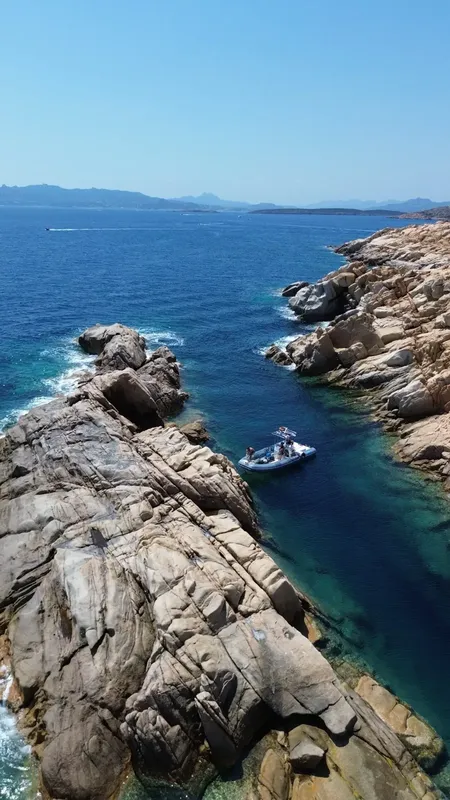 Côte rocheuse, mer bleue, petit bateau de plongée avec des personnes