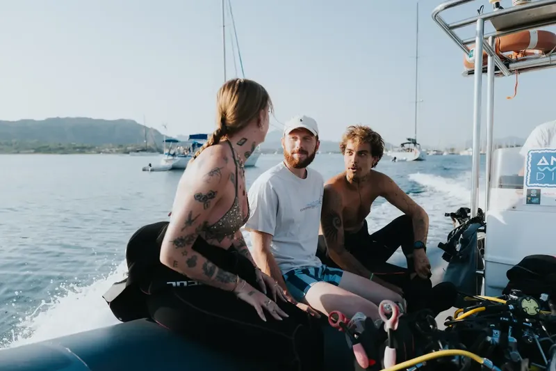 Trois personnes discutent à bord d'un bateau de plongée en mer