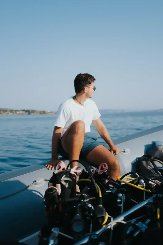 Jeune homme assis sur un bateau de plongée avec équipement